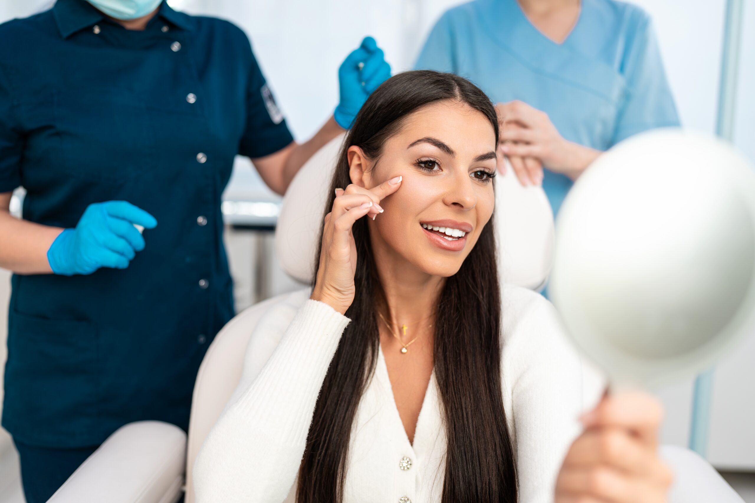 Smiling patient in a treatment chair with clinical staff in the background