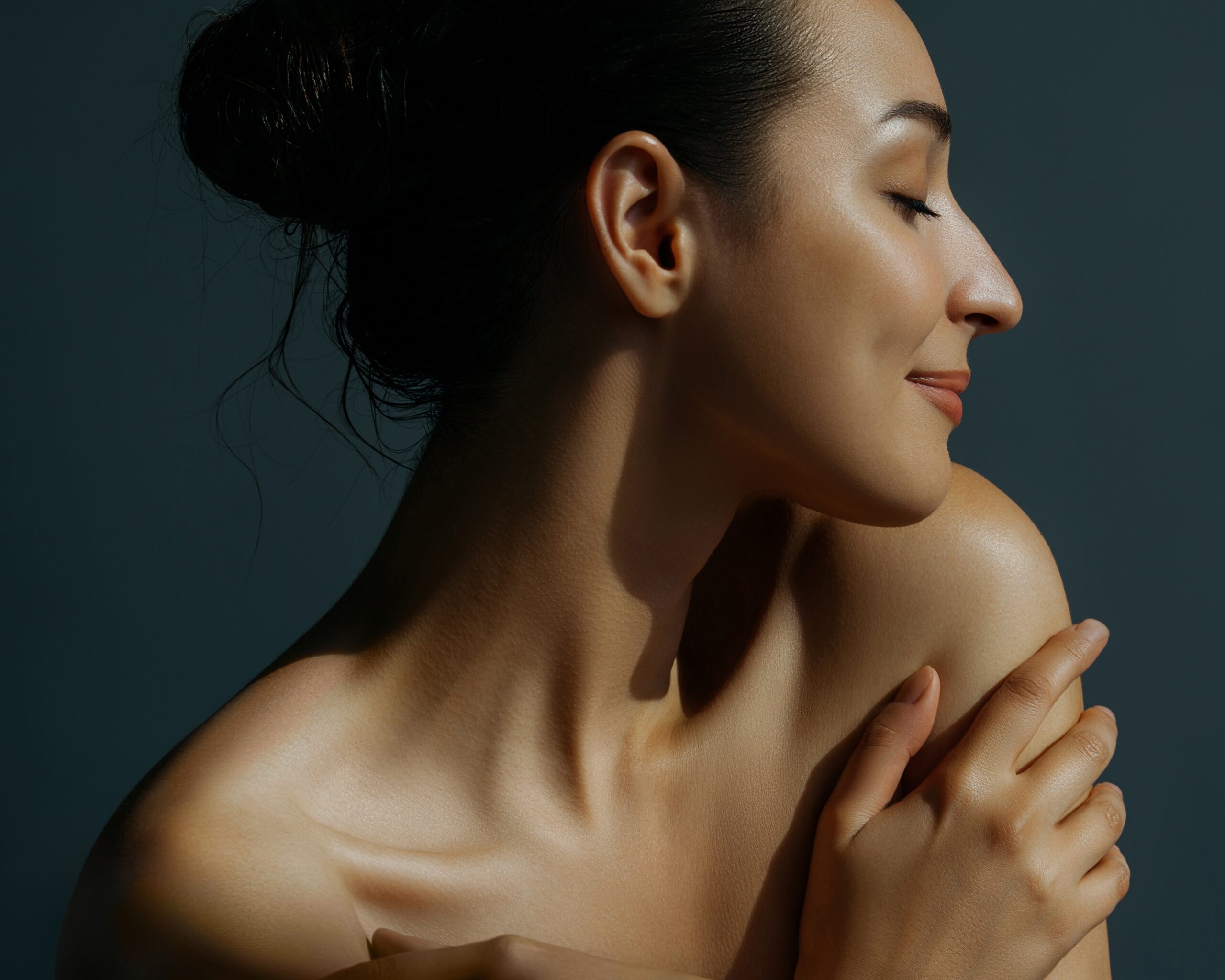 Woman in profile with her hand at her shoulder, calm and confident